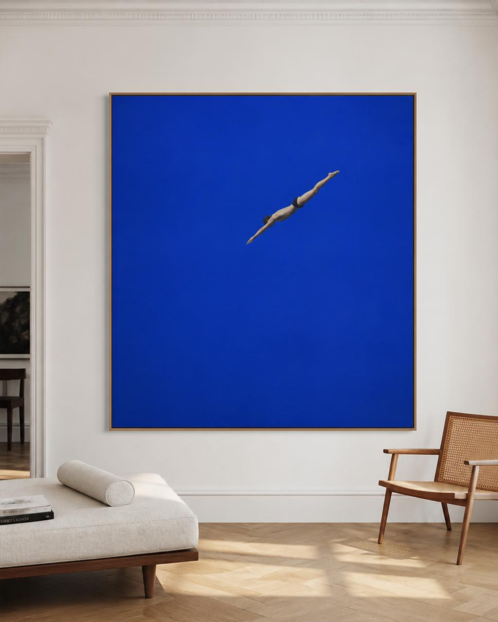 Bright room with white walls and herringbone wood floors, featuring a large frontal blue artwork of a single diving figure