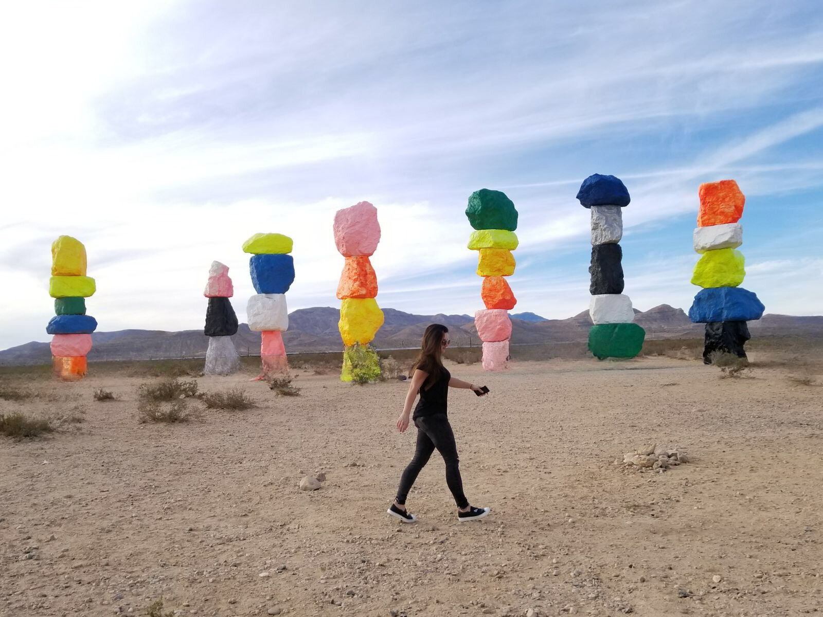 Karol walking past Ugo Rondinone's Seven Magic Mountains in the desert